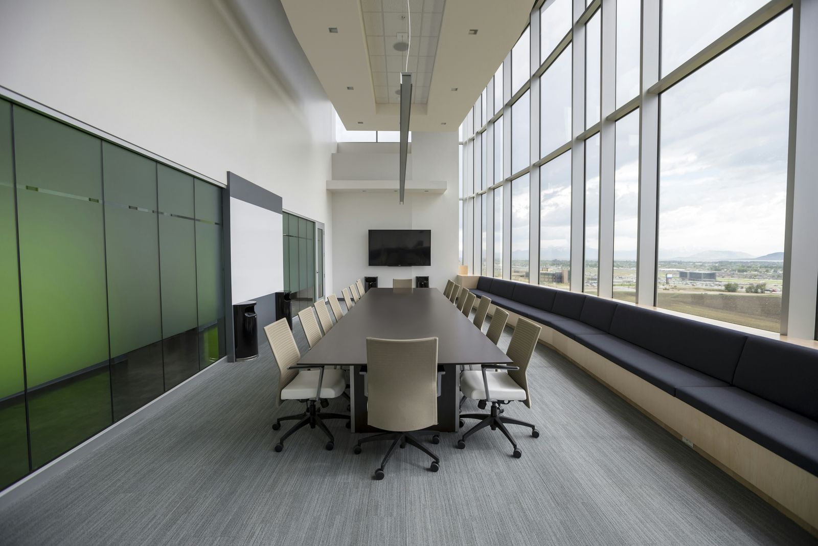 Bright boardroom with a long table and chairs beside a floor-to-ceiling glass wall